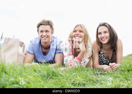 Thoughtful young friends looking away while lying on field Stock Photo