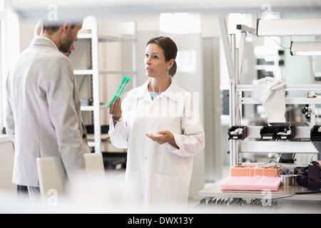 Engineer explaining machine part to businessman in factory Stock Photo