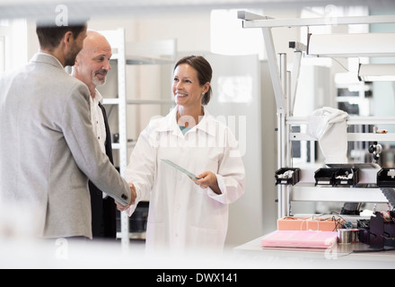 Business people greeting female engineer in manufacturing plant Stock Photo