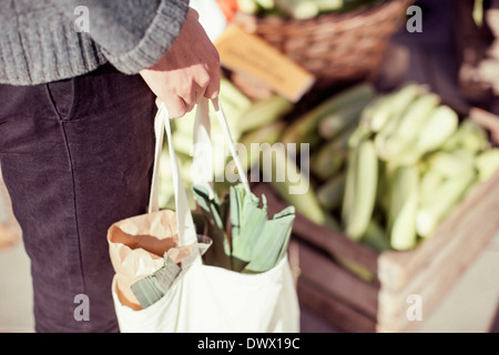 Midsection of man carrying vegetable bag in market Stock Photo