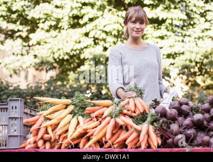 Portrait of smiling female vendor selling vegetables at market stall Stock Photo