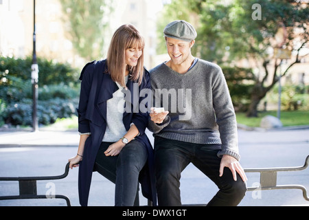 Young couple using mobile phone outdoors Stock Photo