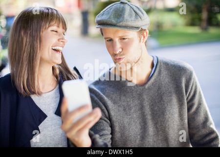 Happy couple photographing themselves through mobile phone outdoors Stock Photo