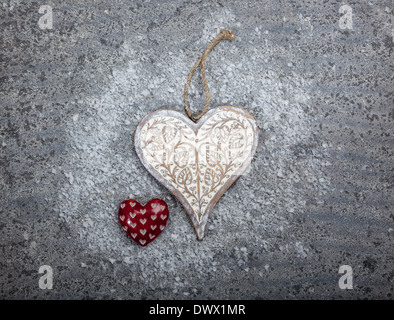 Carved wooden and stone hearts on a grey limestone background Stock Photo