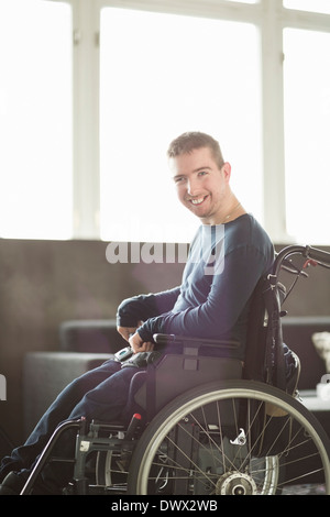 Portrait of happy disabled businessman sitting on motorized wheelchair in office Stock Photo