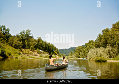 Young women canoeing along river Stock Photo