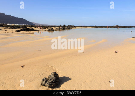 North coast white sand beach with people bathing in shallow tidal pools at low tide Bajo de los Sables Orzola Lanzarote Canaries Stock Photo