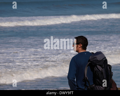 Man with rucksack standing looking out to sea, Westward Ho!, Devon, UK Stock Photo