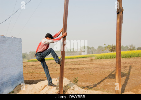 1 Indian Villager Climbing on Pylon Stock Photo