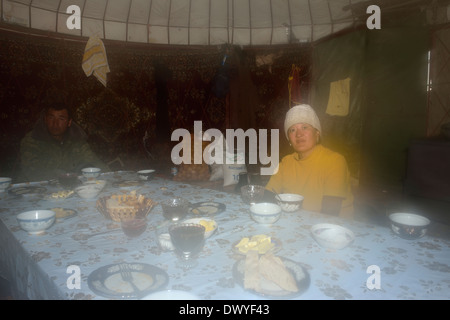 Nomad family having a meal in a yurt by Song Kol lake, Tien Shan Mountains, Kyrgyzstan Stock Photo