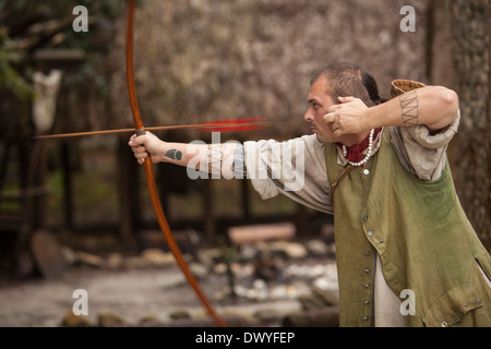 A Timucua native reenactor fires an arrow in St. Augustine Fountain of Youth Archaeological Park in Florida Stock Photo