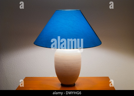 Lamp on a nightstand with a blue glow on a textured wall-diffused lighting Stock Photo