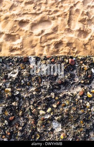 Concrete wall with colorful pebbles and sand Stock Photo