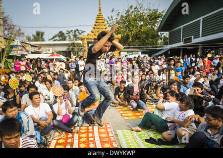 Nakhon Chai Si, Nakhon Pathom, Thailand. 15th Mar, 2014. A man jumps into the air to rush the stage as he goes into a trance state at the Wat Bang Phra tattoo festival. Wat Bang Phra is the best known ''Sak Yant'' tattoo temple in Thailand. It's located in Nakhon Pathom province, about 40 miles from Bangkok. The tattoos are given with hollow stainless steel needles and are thought to possess magical powers of protection. The tattoos, which are given by Buddhist monks, are popular with soldiers, policeman and gangsters, people who generally live in harm's way. The tattoo must be activated to Stock Photo