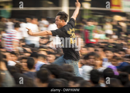 Nakhon Chai Si, Nakhon Pathom, Thailand. 15th Mar, 2014. A man in a trance rushes the stage at the Wat Bang Phra tattoo festival. Wat Bang Phra is the best known ''Sak Yant'' tattoo temple in Thailand. It's located in Nakhon Pathom province, about 40 miles from Bangkok. The tattoos are given with hollow stainless steel needles and are thought to possess magical powers of protection. The tattoos, which are given by Buddhist monks, are popular with soldiers, policeman and gangsters, people who generally live in harm's way. The tattoo must be activated to remain powerful and the annual Wai Khru Stock Photo