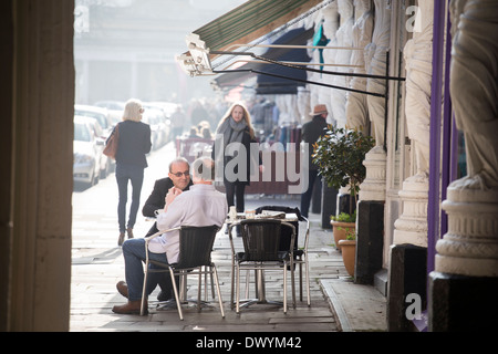 Two men sitting outside at a pavement cafe on Montpellier Street in Cheltenham, UK Stock Photo