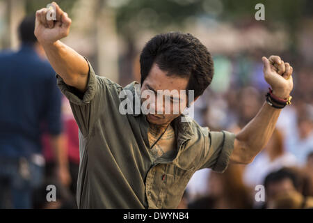 Nakhon Chai Si, Nakhon Pathom, Thailand. 15th Mar, 2014. A man in a trance rushes the stage at the Wat Bang Phra tattoo festival. Wat Bang Phra is the best known ''Sak Yant'' tattoo temple in Thailand. It's located in Nakhon Pathom province, about 40 miles from Bangkok. The tattoos are given with hollow stainless steel needles and are thought to possess magical powers of protection. The tattoos, which are given by Buddhist monks, are popular with soldiers, policeman and gangsters, people who generally live in harm's way. The tattoo must be activated to remain powerful and the annual Wai Khru Stock Photo