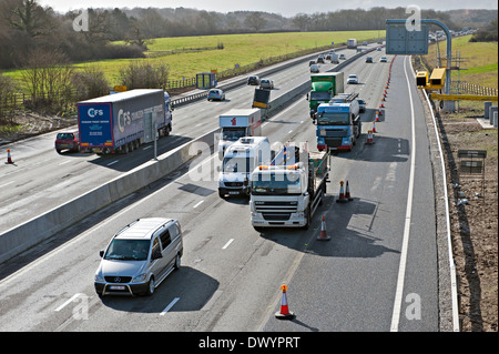 Traffic passing a coned off area on the M25 motorway in Surrey, UK Stock Photo