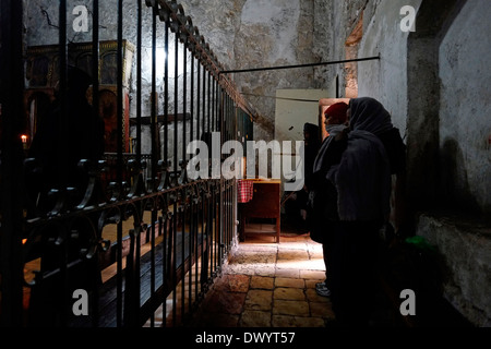 Ethiopian Orthodox Christians praying inside the Coptic Chapel of St. Michael the Archangel in the lower section of the Ethiopian church in the lower section of the Ethiopian church beneath Deir El-Sultan monastery which is located on the roof of the Church of Holy Sepulchre in old city of East Jerusalem Israel Stock Photo
