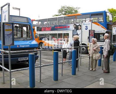 People including elderly man & woman with walking sticks queueing & waiting at Chichester bus station Chichester West Sussex UK Stock Photo