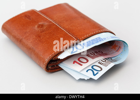 Old brown leather purse wallet stuffed full with Euro notes on a plain background. Europe Stock Photo