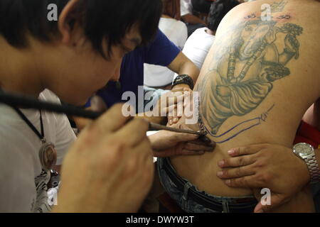 Nakhon Pathom , Thailand. 15th Mar 2014. Thousands of believers from all over Thailand come to take partto the temple's monks who are master tattooist. In Thai culture the tattoo is worn as a symbol of spiritual and physical protection, many believe that the tattoo has mystical powers. Many tattoo fanatics choose to have monkeys and tigers as well as the Khmer/Cambodia ancient script on their bodies. Credit:  John Vincent/Alamy Live News Stock Photo