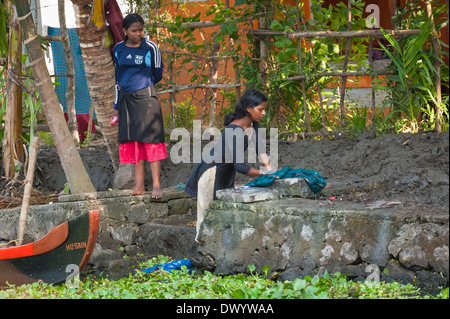 indian women and girls washing clothes by hand in a lake