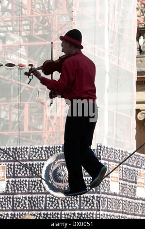 Busker on tightrope playing violin, Bath, Somerset, England, UK Stock Photo