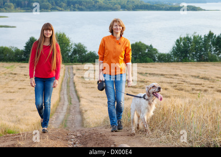 mother and her daughter with dog walking near lake Stock Photo