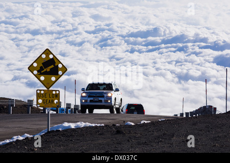 Car on Mauna Kea summit road, clouds in background. Big Island of Hawaii. Stock Photo