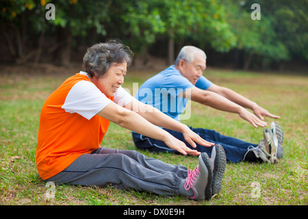Happy elderly seniors couple working out on a meadow in park Stock Photo