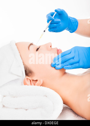 Beautiful woman gets injection in her face over white background Stock Photo