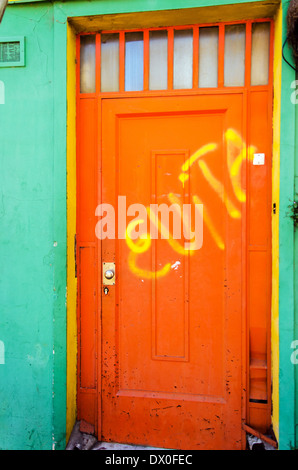 An orange door with graffiti scrawled on it in La Boca neighborhood in Buenos Aires, Argentina Stock Photo