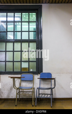 Pair of old chairs and desks in an old worn down classroom Stock Photo