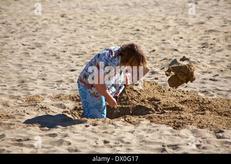 man digging a deep hole in the sand at Bournemouth beach, Bournemouth, Dorset UK  in March Stock Photo