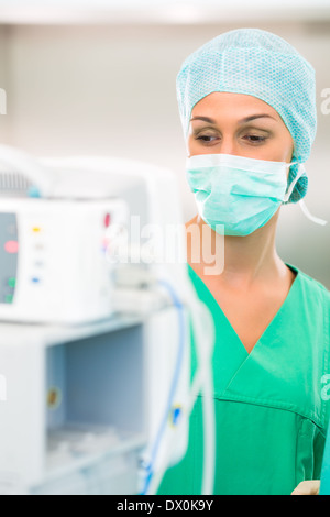 Surgeon doctor in sterile operating room or operation theater checking data on heart monitor in emergency situation Stock Photo