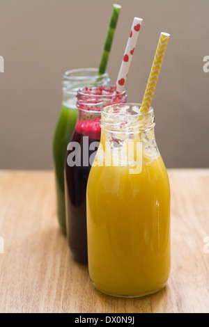 Three freshly squeezed juices in glass bottles. Stock Photo
