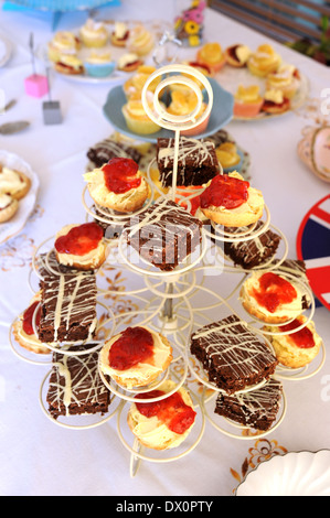 Vintage cream afternoon tea with sandwiches and cakes laid out on a table Stock Photo