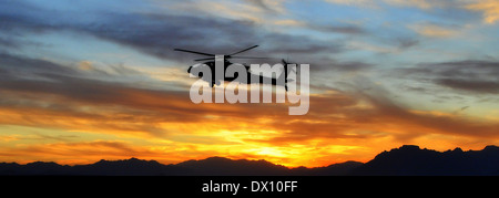 A US Army AH-64 Apache attack helicopter, assigned to Task Force Brawler returns to base at sunset after a mission in the Uruzgan Valley January 18, 2013 in Tarin Kowt, Afghanistan. Stock Photo