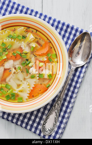 Chicken soup with pasta Farfalle in the bowl on wooden table Stock Photo