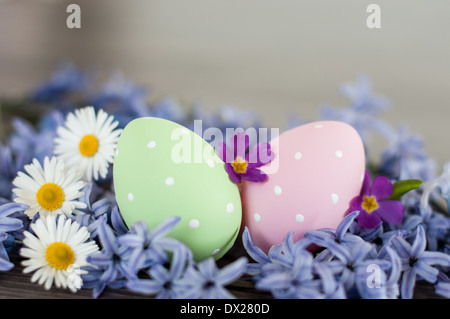 Spring in Easter- two Easter eggs- pink and green polka-dot and different spring flowers. Stock Photo