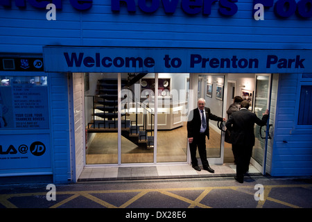 The doorman welcoming two visitors at the main entrance of Prenton Park home of Tranmere Rovers Football Club.