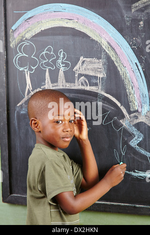 African boy drawing colorful picture on a blackboard in kindergarten Stock Photo