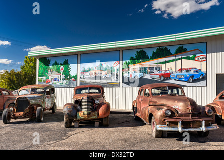 Old, rusted cars for sale, murals behind on wall of service station, in Delta, Colorado, USA Stock Photo