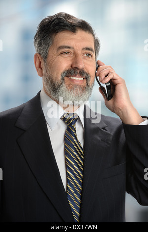 Portrait of senior Hispanic businessman using cell phone inside office Stock Photo