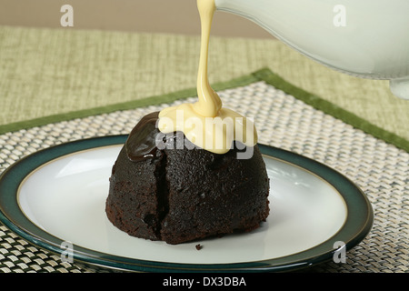 dark chocolate sponge dessert with pouring custard Stock Photo