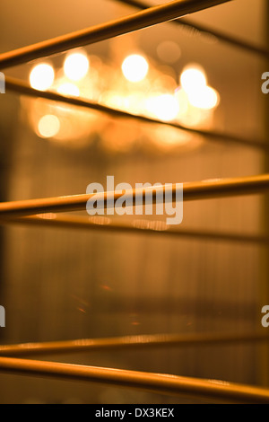 Abstract grill work with illuminated chandelier in background, close up Stock Photo