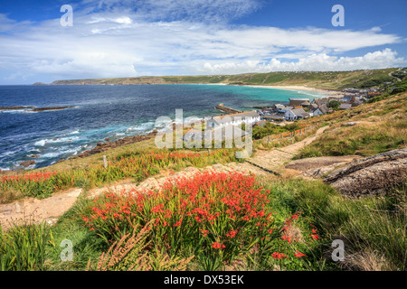 Sennen Cove in Cornwall with a display a Montbretia in the foreground Stock Photo