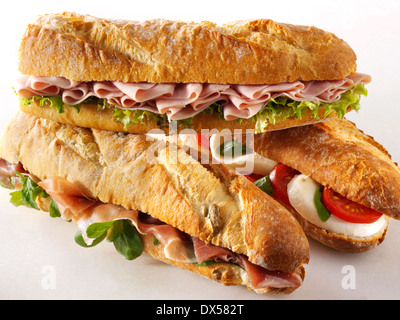 Bread baguettes filled with mozerella & tomatoes, ham & salad, Prcutto ham & rocket. Stock Photo