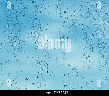 Abstract - Sky and clouds behind rain drops on a window Stock Photo